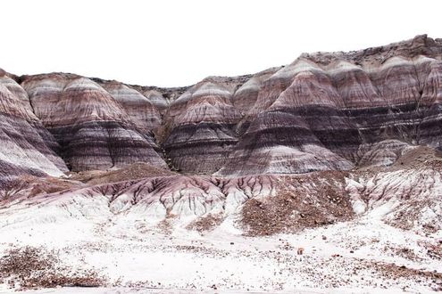 A large rock in the middle of a desert with mountains in the background
