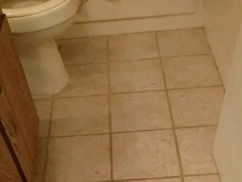 Before - Cleaning a beige tile floor in a bathroom