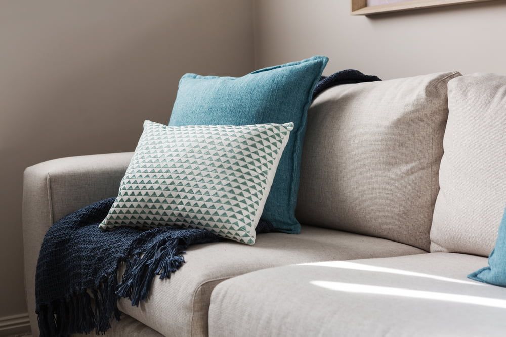 Beige sofa with teal and white throw pillows.