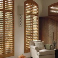 Sunlit living room with arched wooden shutters and a white armchair by the wall