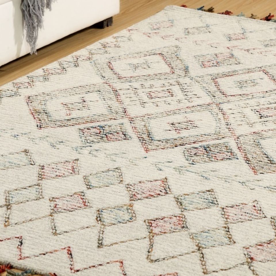 Cream rug with subtle geometric pattern on a light wood floor in a living room.