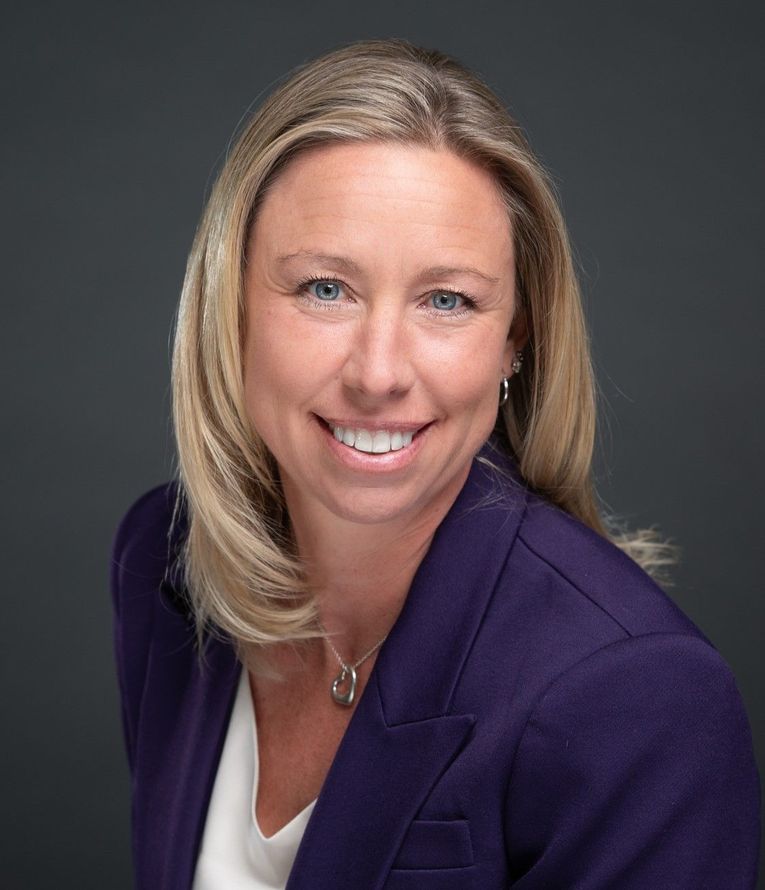 A woman is wearing a purple jacket and smiling for the camera.