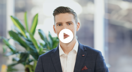 A man in a suit and white shirt is standing in front of a window with a play button on his face.