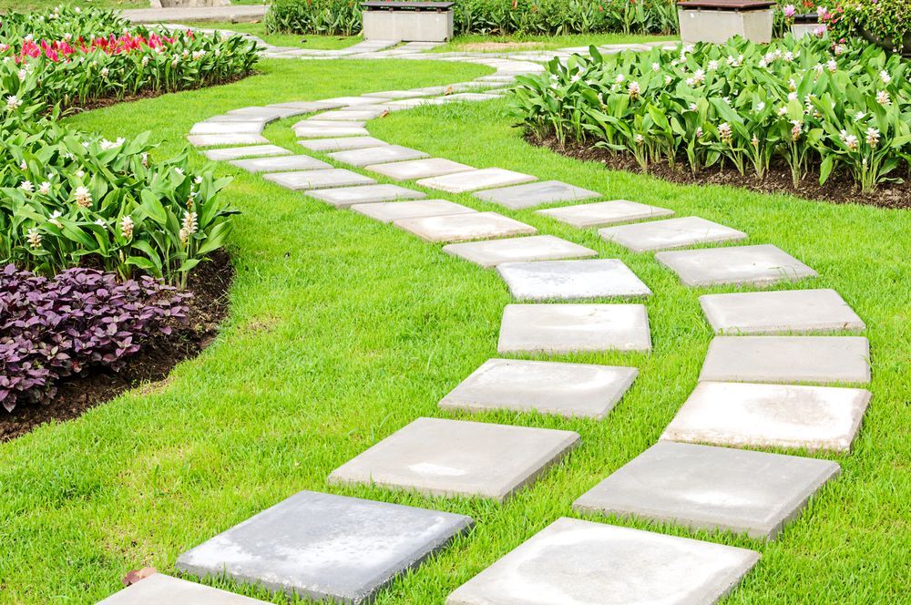 Stone Pathway Curves Through a Green Garden, Surrounded by Flowers and Grass — All Around Concreting in Wollongbar, NSW
