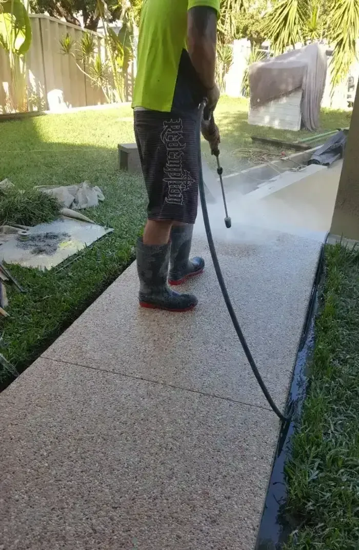 Person Power Washing a Concrete Walkway in a Yard, Wearing Boots and Neon Shirt — All Around Concreting in Wollongbar, NSW