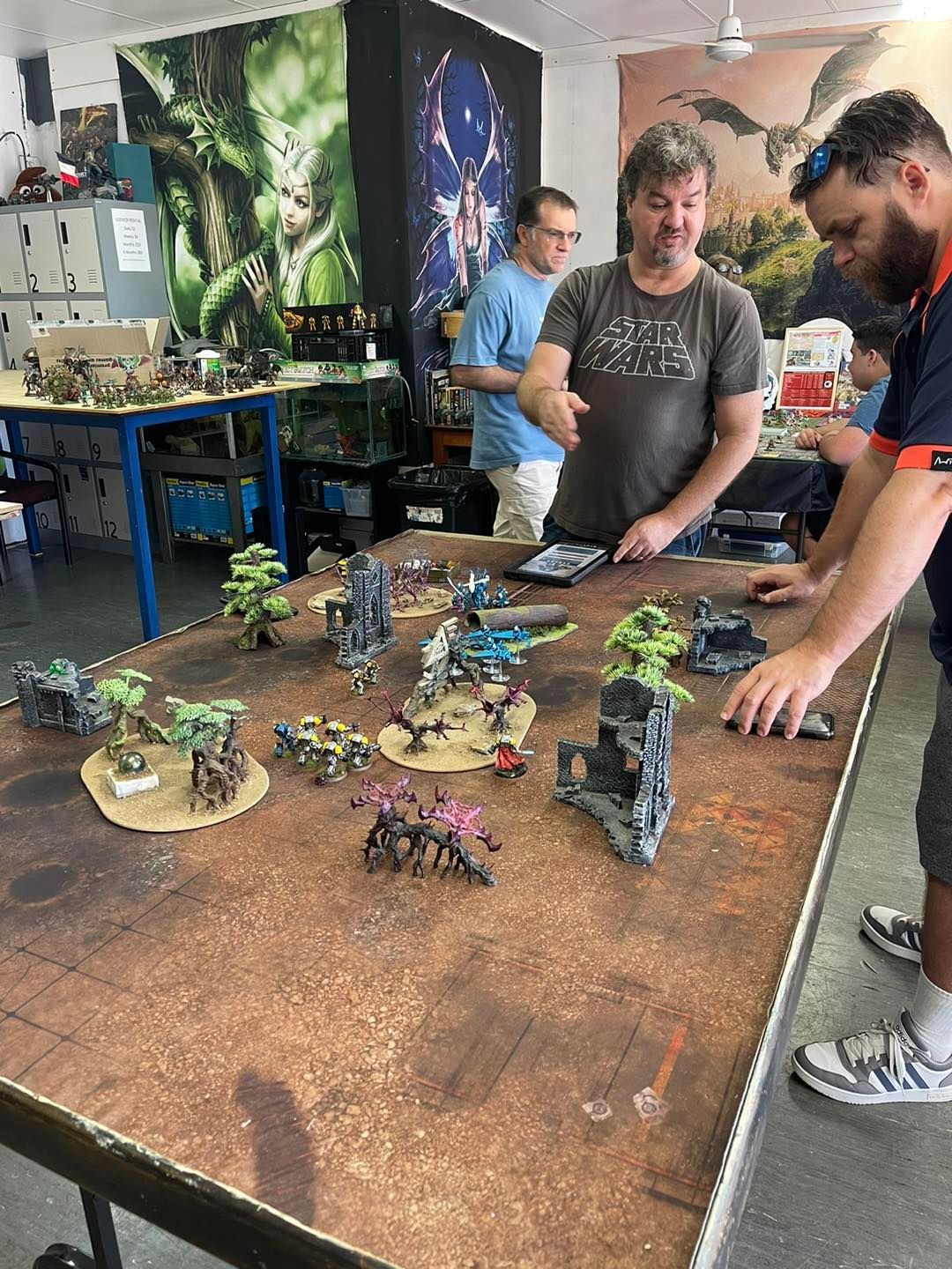 People Playing a Tabletop Wargame With Miniatures on a Large, Brown Mat — Grim Gaming & Hobbies in Bundaberg Central, QLD