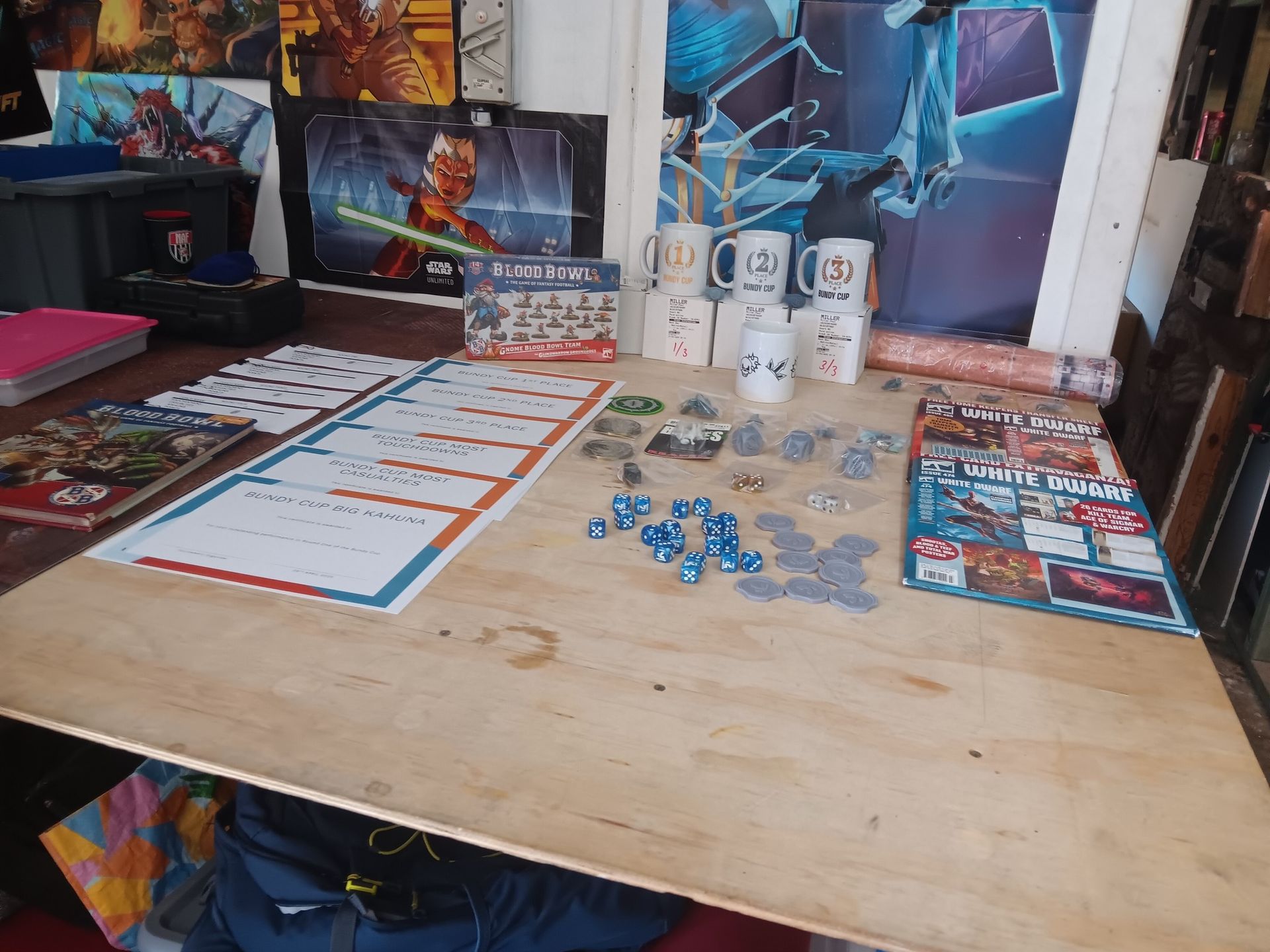 Wooden Table With Board Games, Dice, Miniatures, and Star Wars Posters — Grim Gaming & Hobbies in Bundaberg Central, QLD