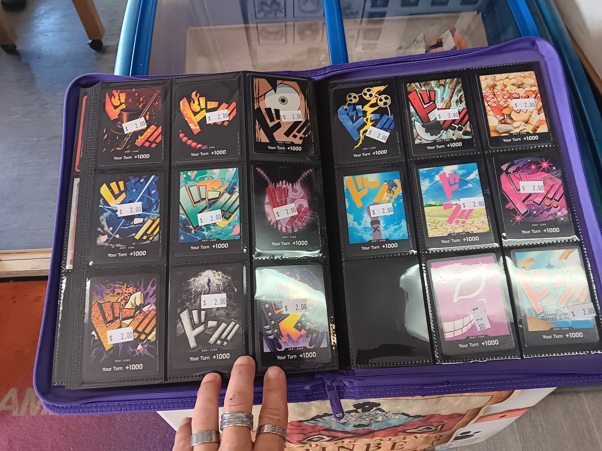 A Hand Points to a Binder of Black Trading Cards — Grim Gaming & Hobbies in Bundaberg Central, QLD