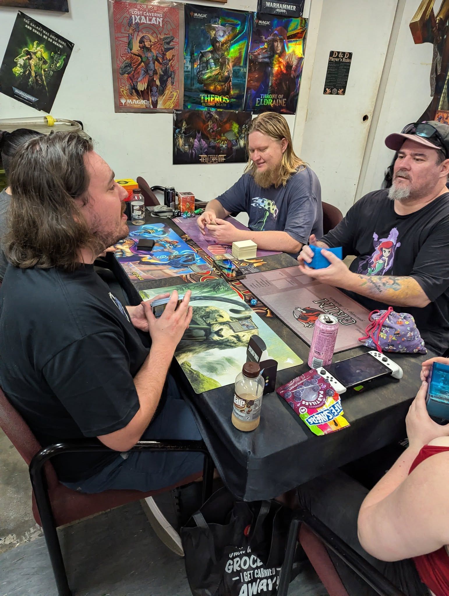 People Playing a Tabletop Game at a Table Covered in Game Mats — Grim Gaming & Hobbies in Bundaberg Central, QLD