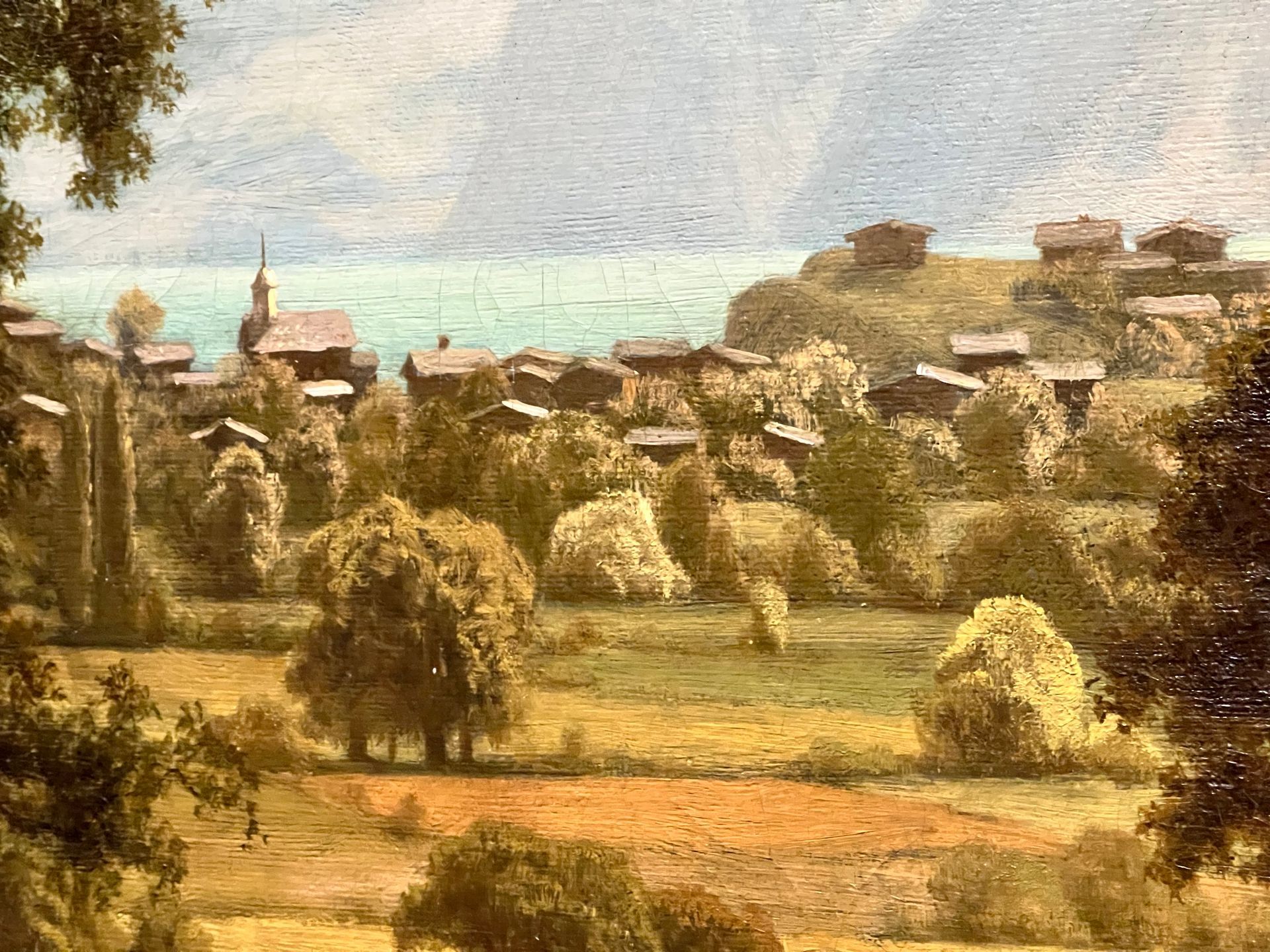A close-up of a painting of a landscape with a village in the background.