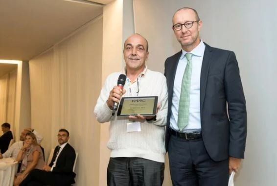 Due uomini sono in piedi uno accanto all'altro e tengono in mano un microfono e un tablet.