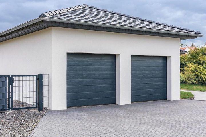 Un garage bianco con due porte nere e un tetto.