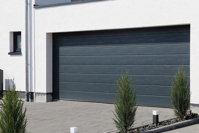 Una porta da garage nera è posta di fronte a una casa bianca.