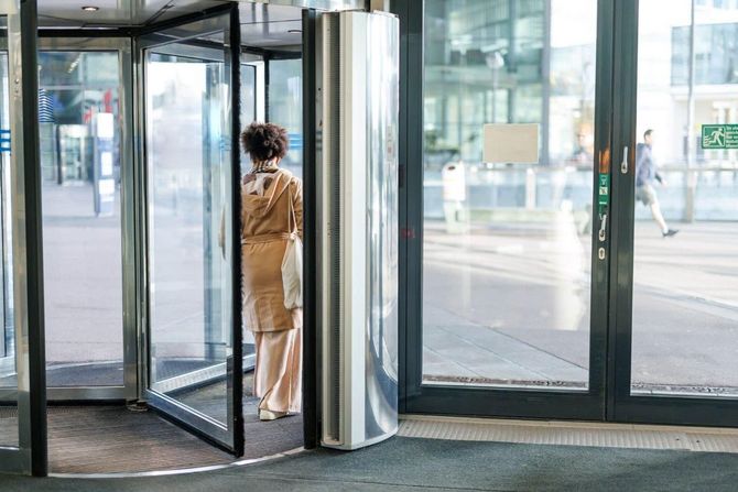 Una donna è in piedi in una porta girevole.