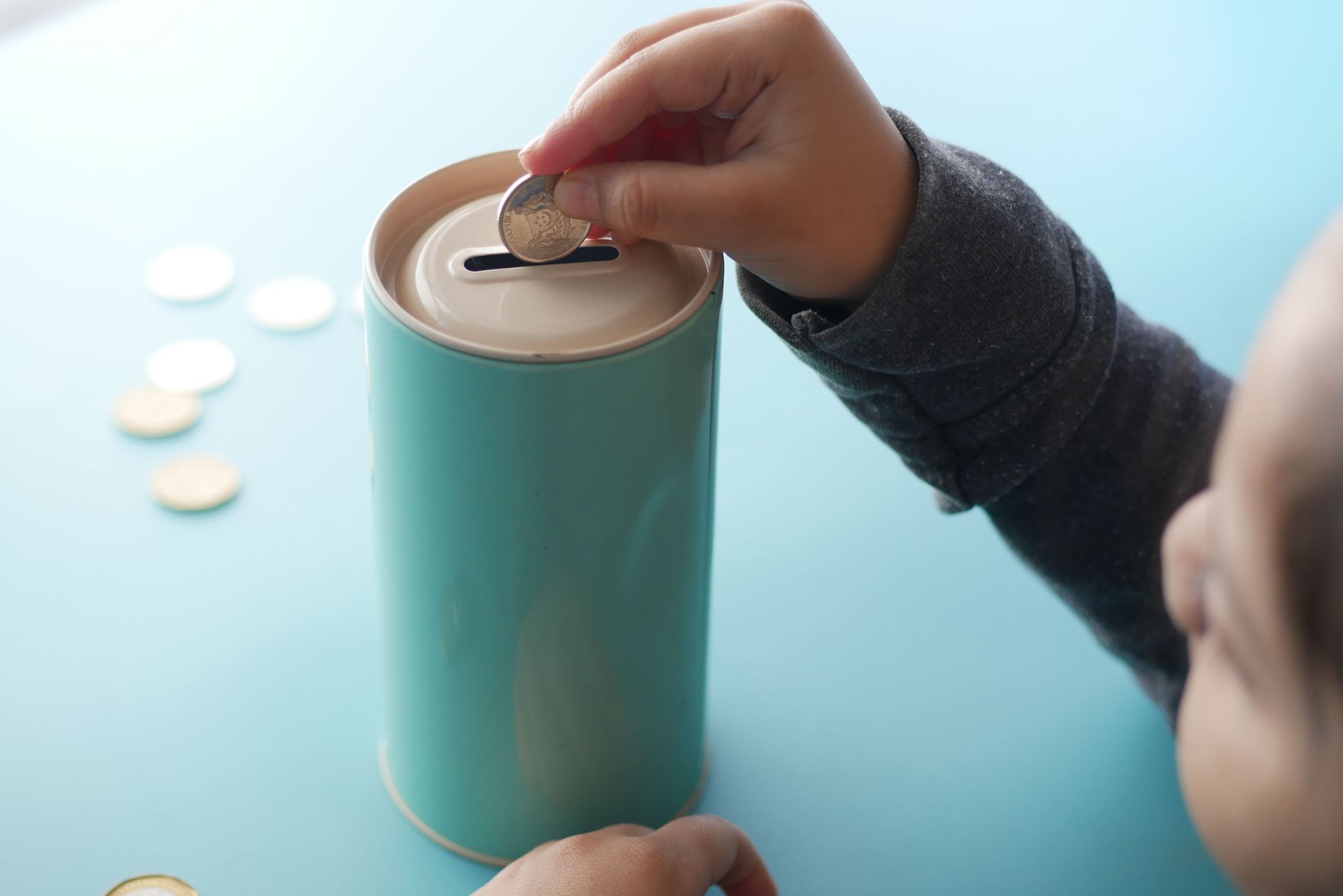 Child placing a coin into a savings tin for future family planning.