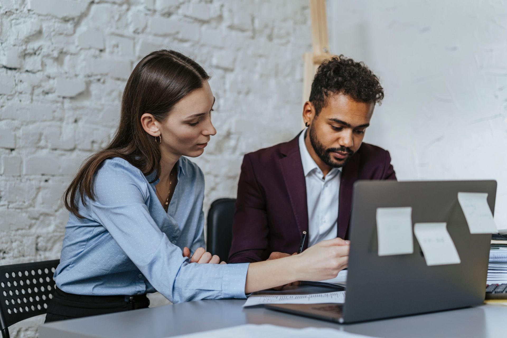 Mid-career professionals comparing pension and ISA investment options beside a laptop.