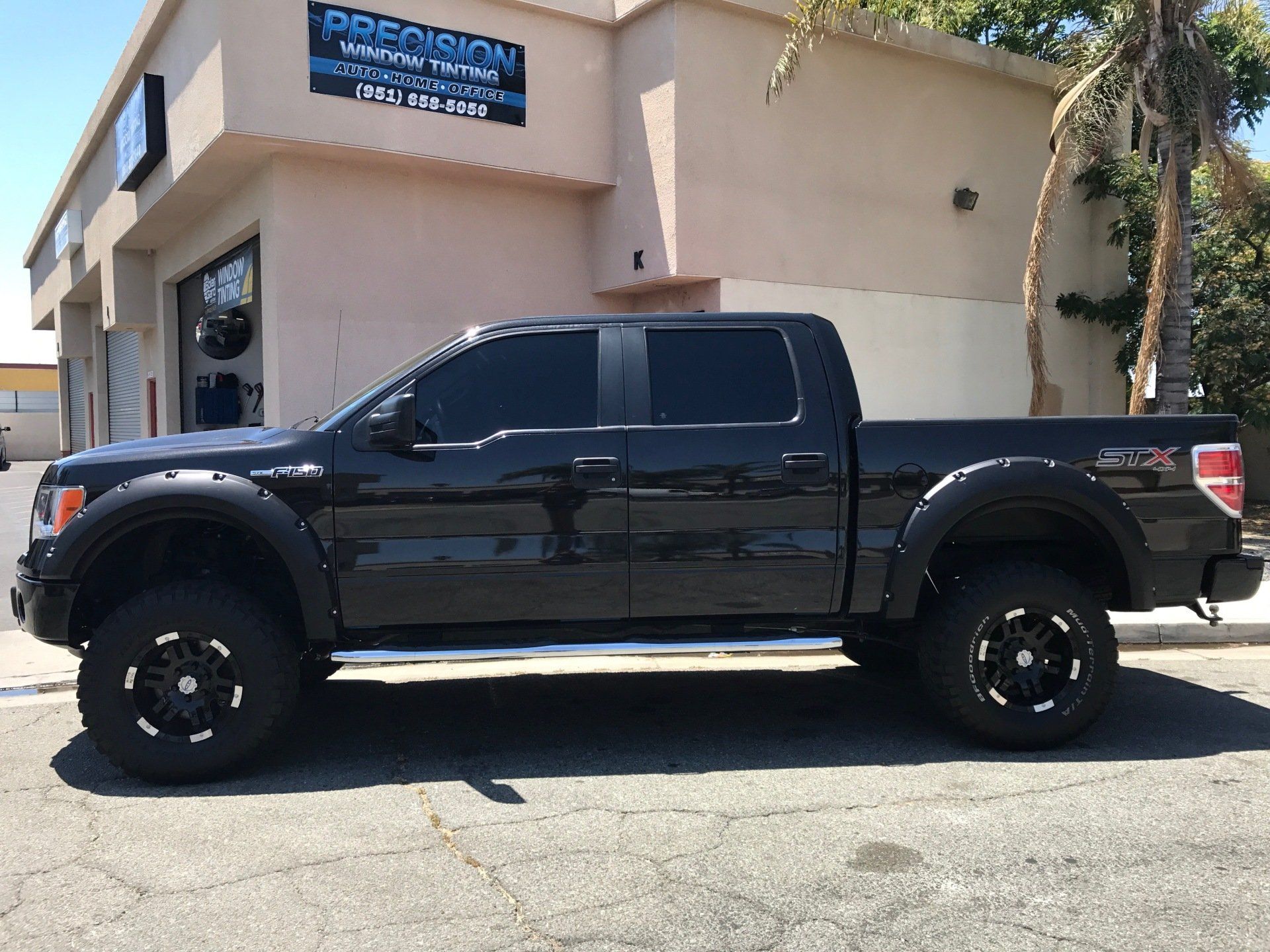 A black truck is parked in front of a building