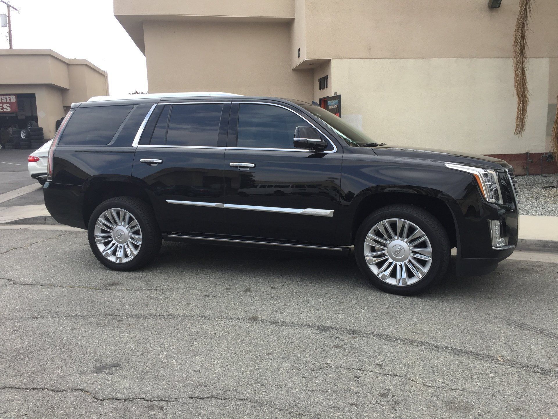 A black Cadillac Escalade is parked in front of a building