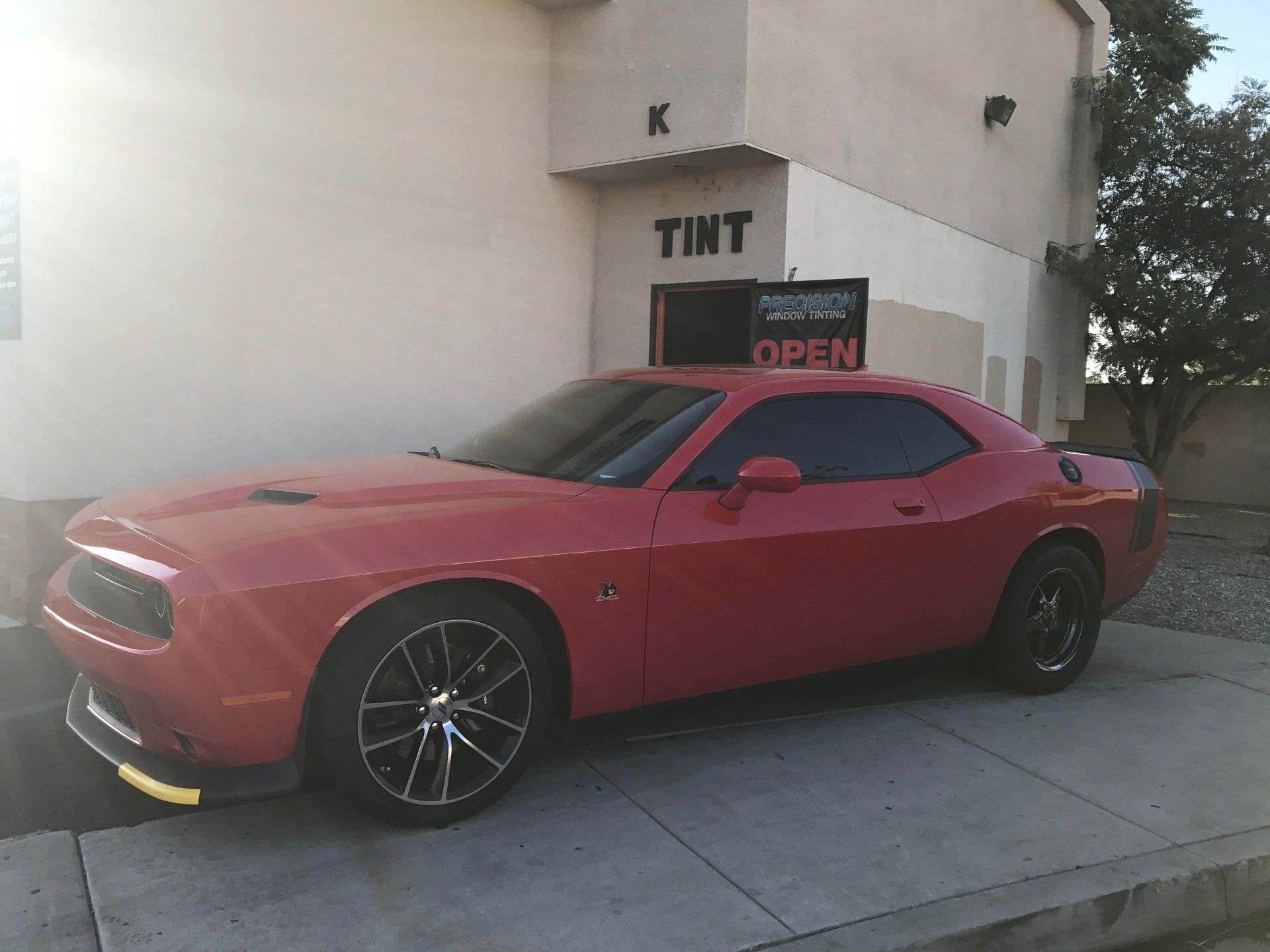 A red car is parked in front of a building that says tint
