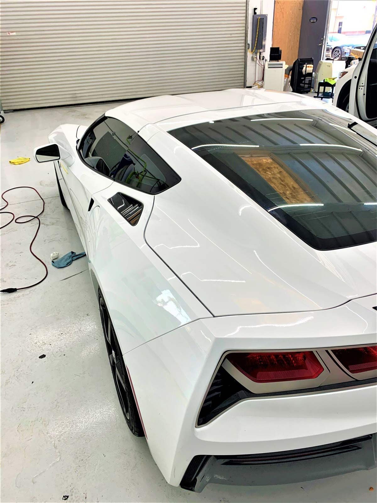 A black car is parked in front of a tint shop.