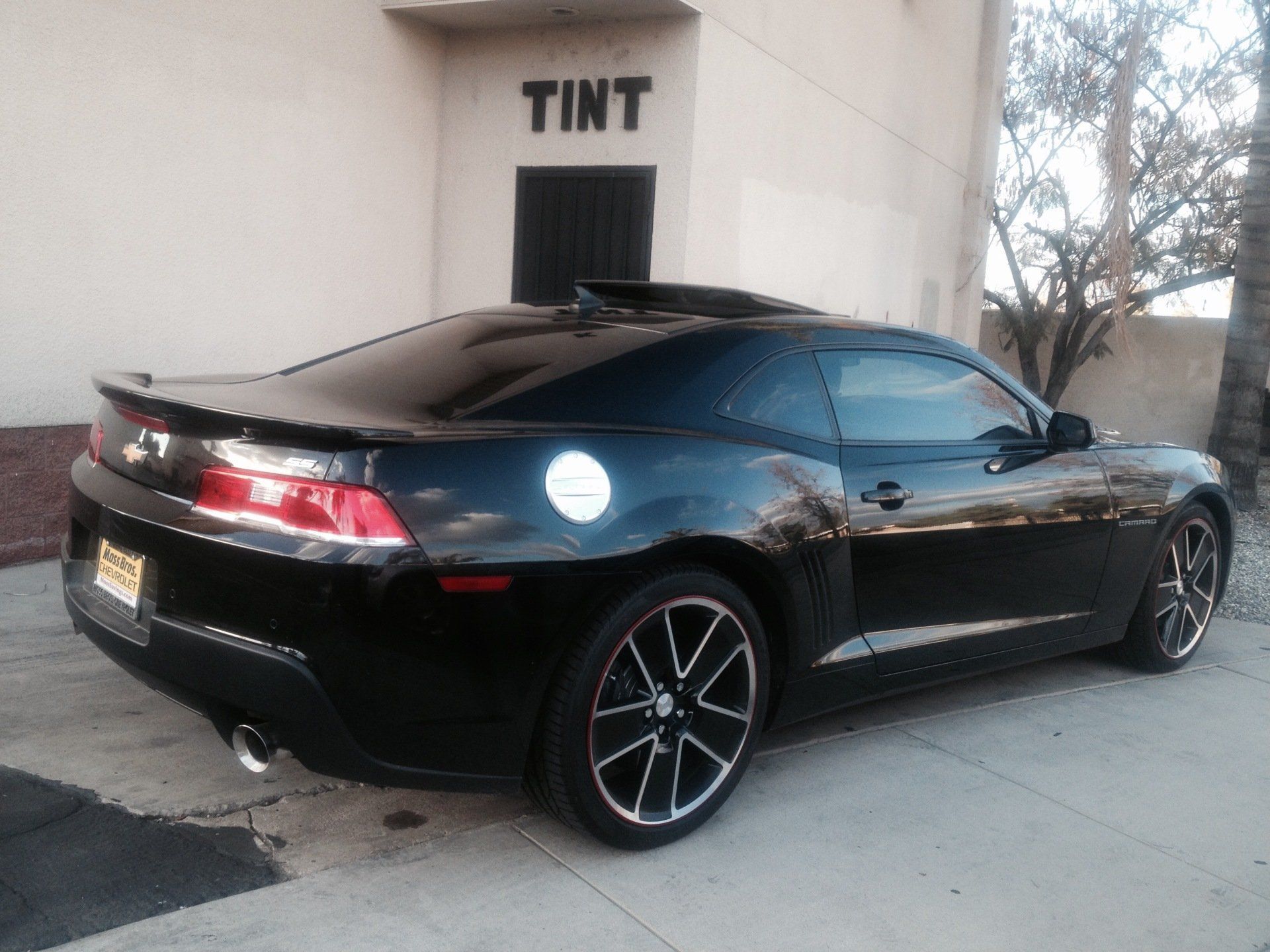 A black car is parked in front of a building that says tint