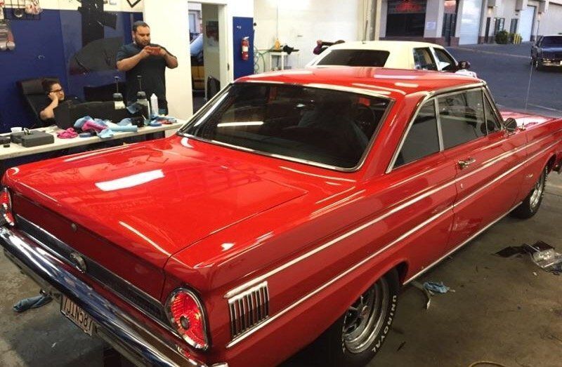 A red car is parked in a garage next to a white car