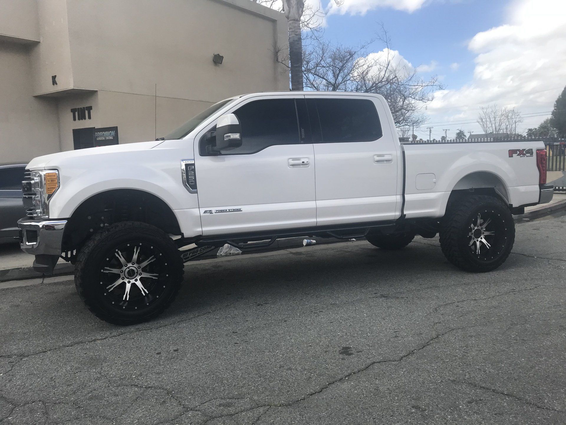 A white truck is parked on the side of the road in front of a building