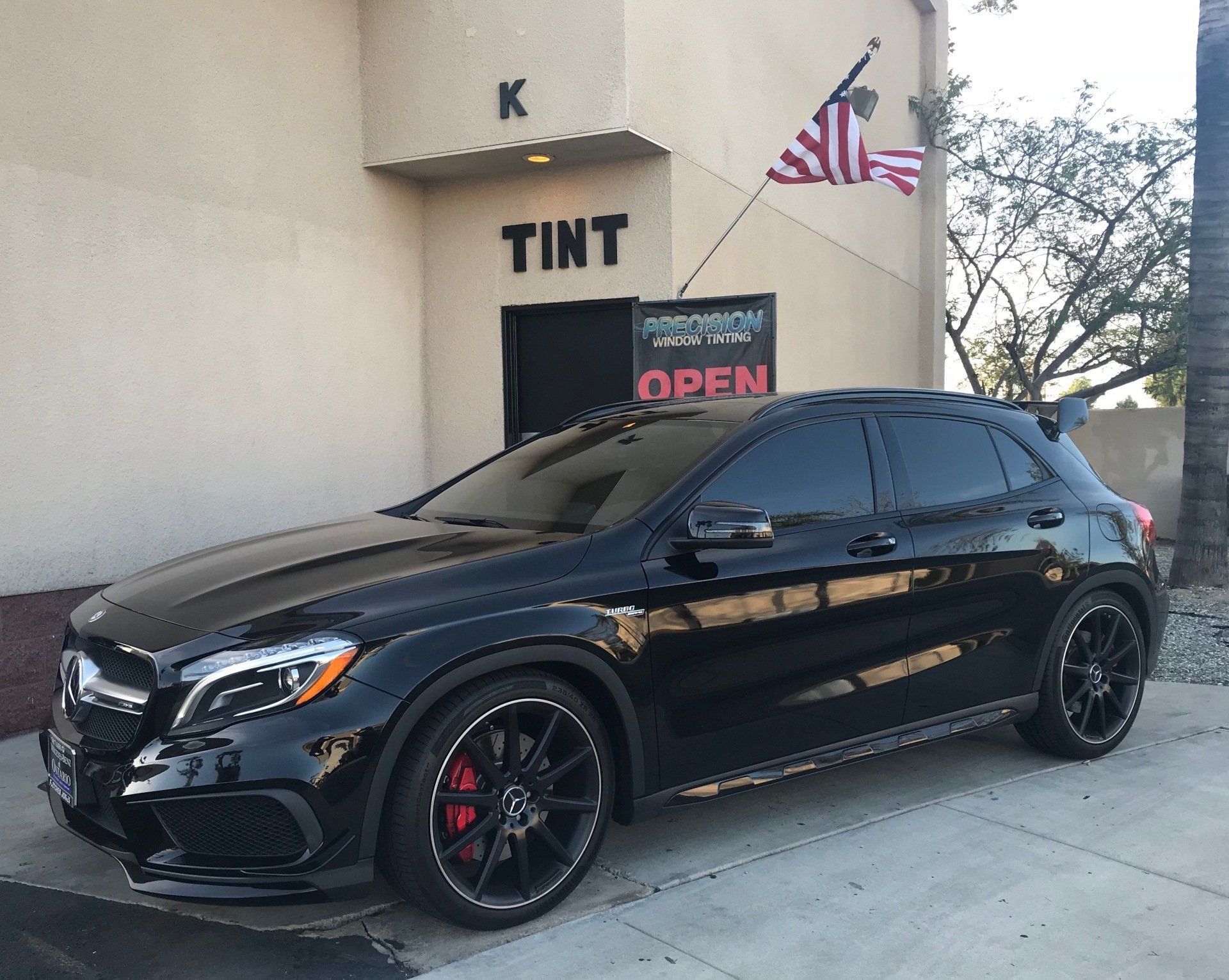 A black car is parked in front of a building that says tint