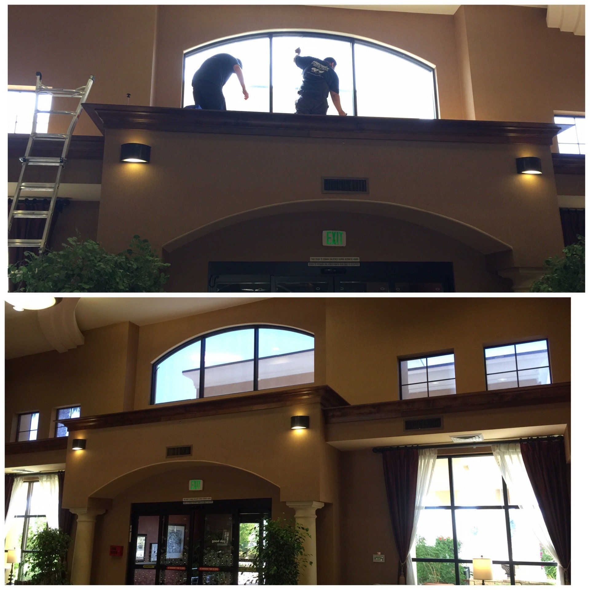 Two men are cleaning a window in a building