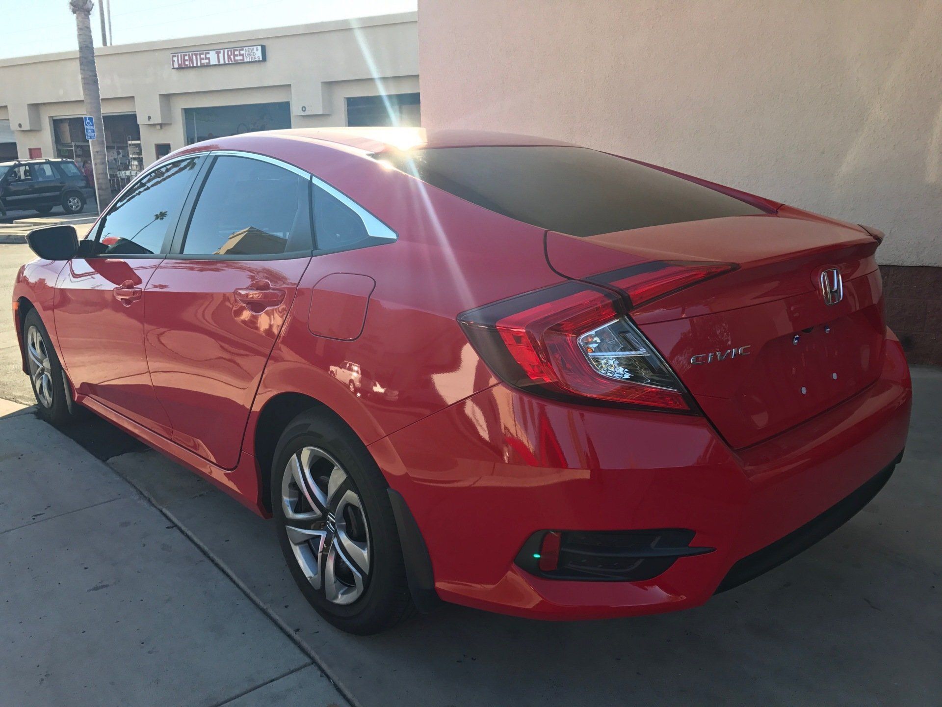 A red Honda Civic is parked in front of a building