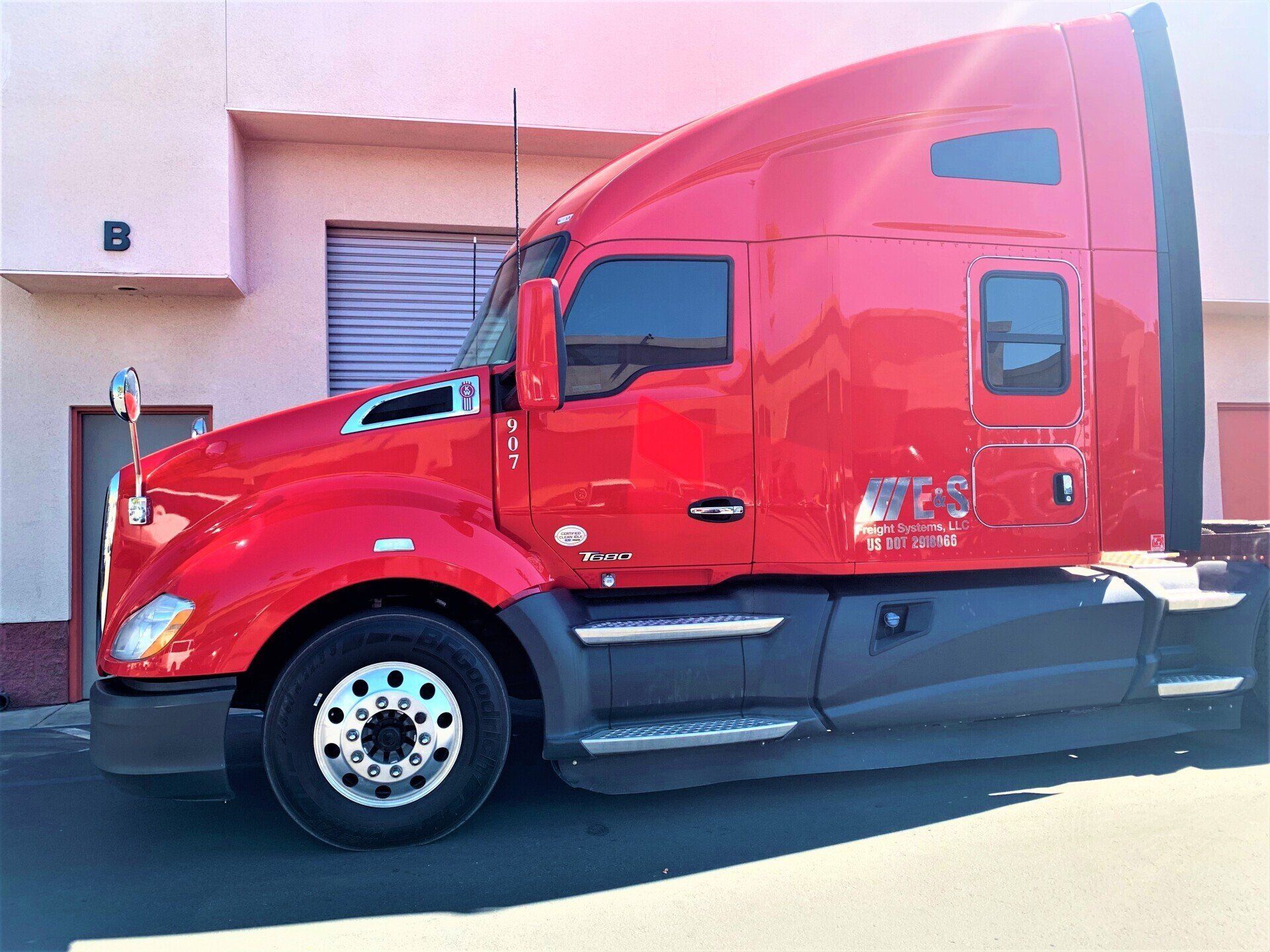 A red semi truck is parked in front of a building
