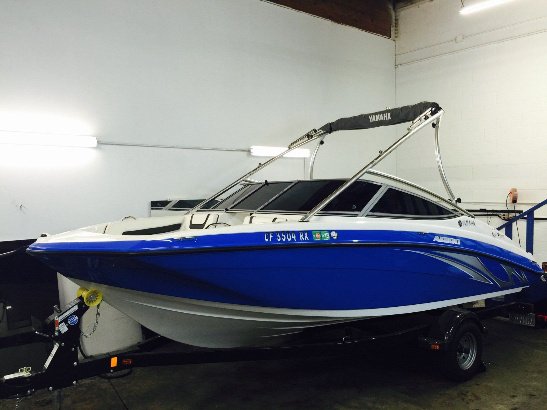 A blue and white boat with a roof is parked in a garage
