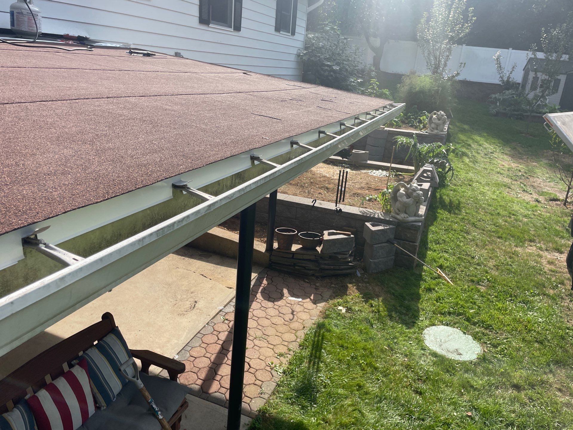 A patio with a bench under a roof with a red roof.
