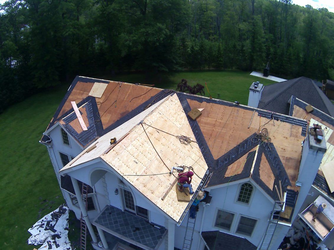 A man is working on a roof with a blue tarp.