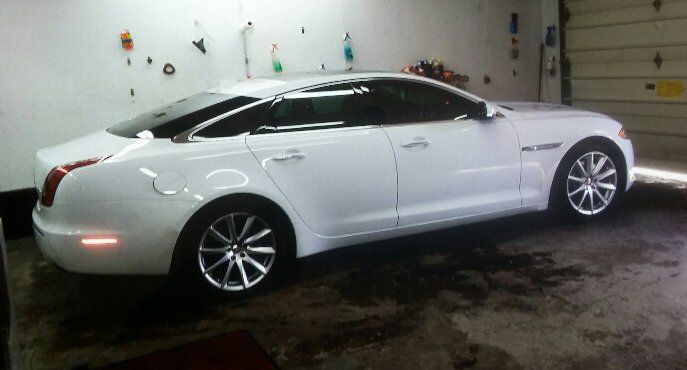 A white car is parked in a garage next to a garage door
