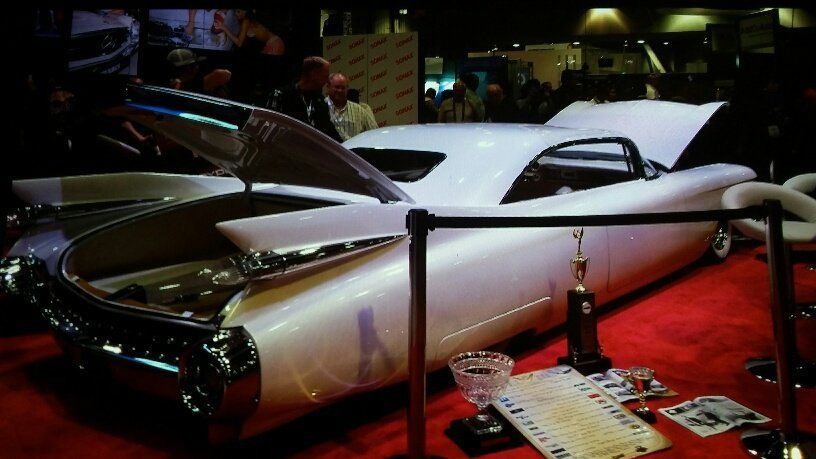 A white car with the hood up is sitting on a red carpet