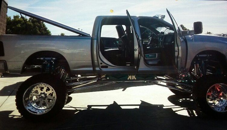 A silver truck with the doors open is parked in a parking lot