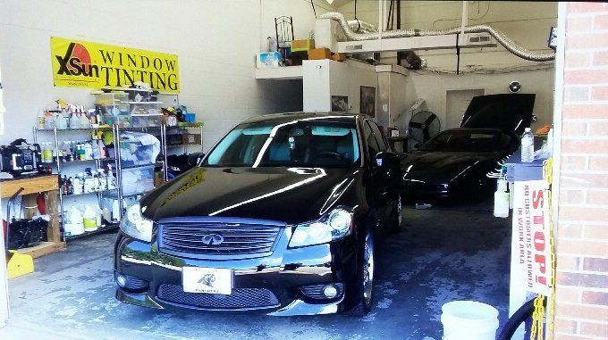 A black car is parked in a garage next to a sign that says window tinting