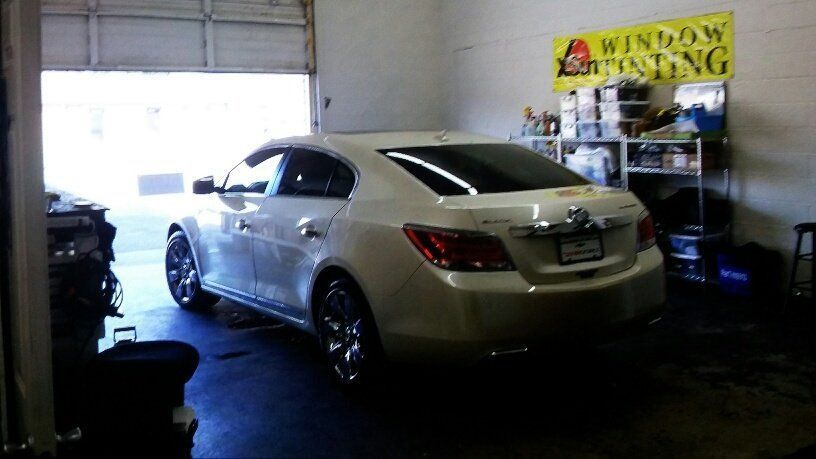 A white car is parked in a garage next to a sign that says window tinting
