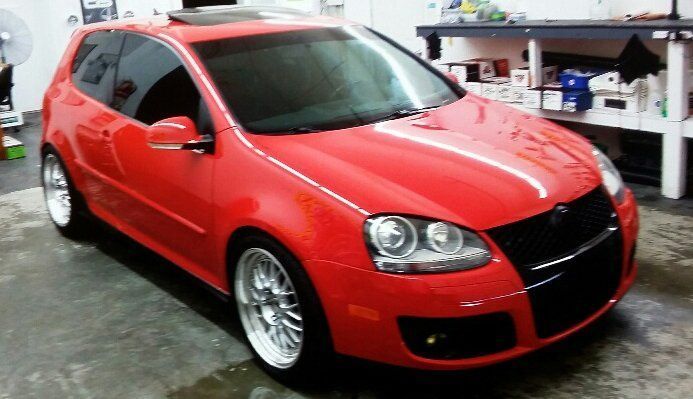 A red volkswagen golf is parked in a garage