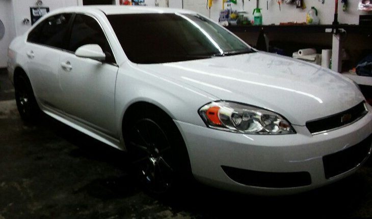 A white car with black wheels is parked in a garage