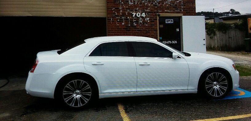 A white car is parked in front of a building with the number 704 on it