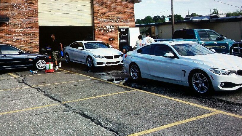 A group of cars are parked in a parking lot in front of a building.