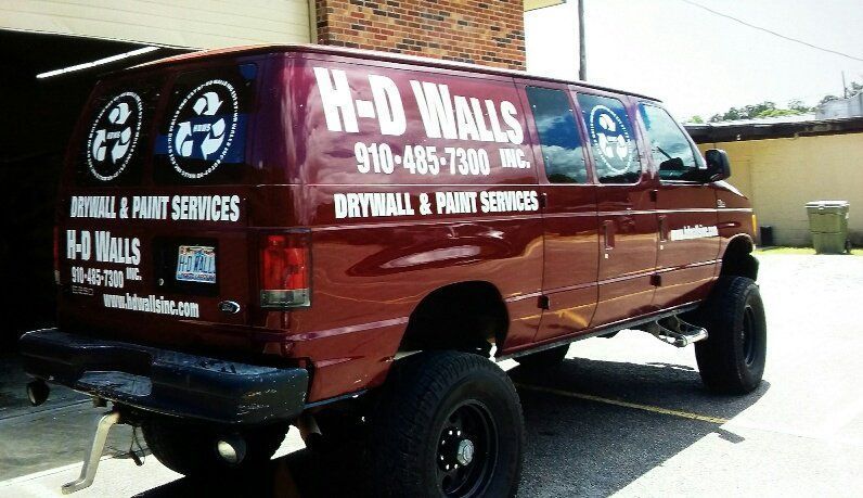 A red van for h-d walls is parked in a parking lot