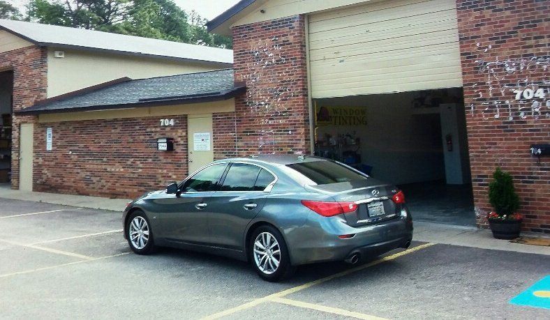A car is parked in a handicapped parking spot in front of a brick building.