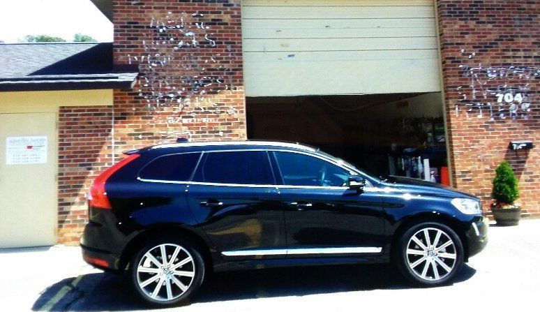 A black suv is parked in front of a brick building with the number 704 on it