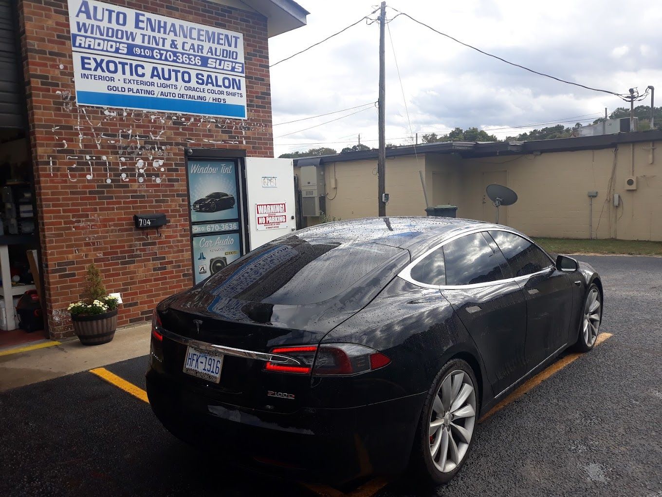 A black tesla model s is parked in front of a brick building.