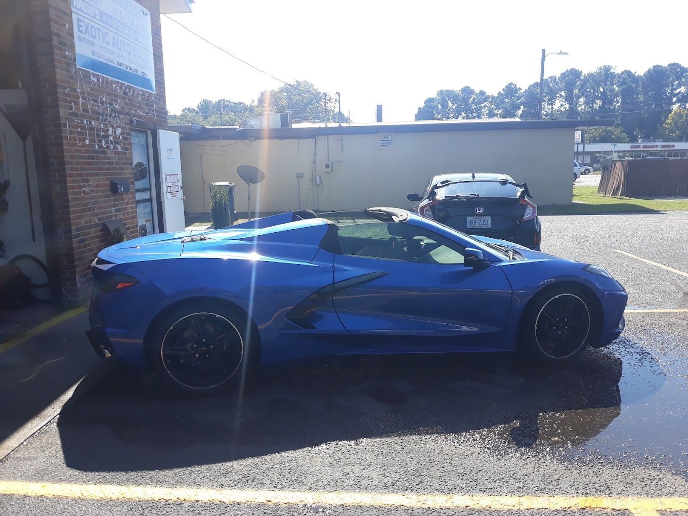 A blue sports car is parked in a parking lot in front of a building.