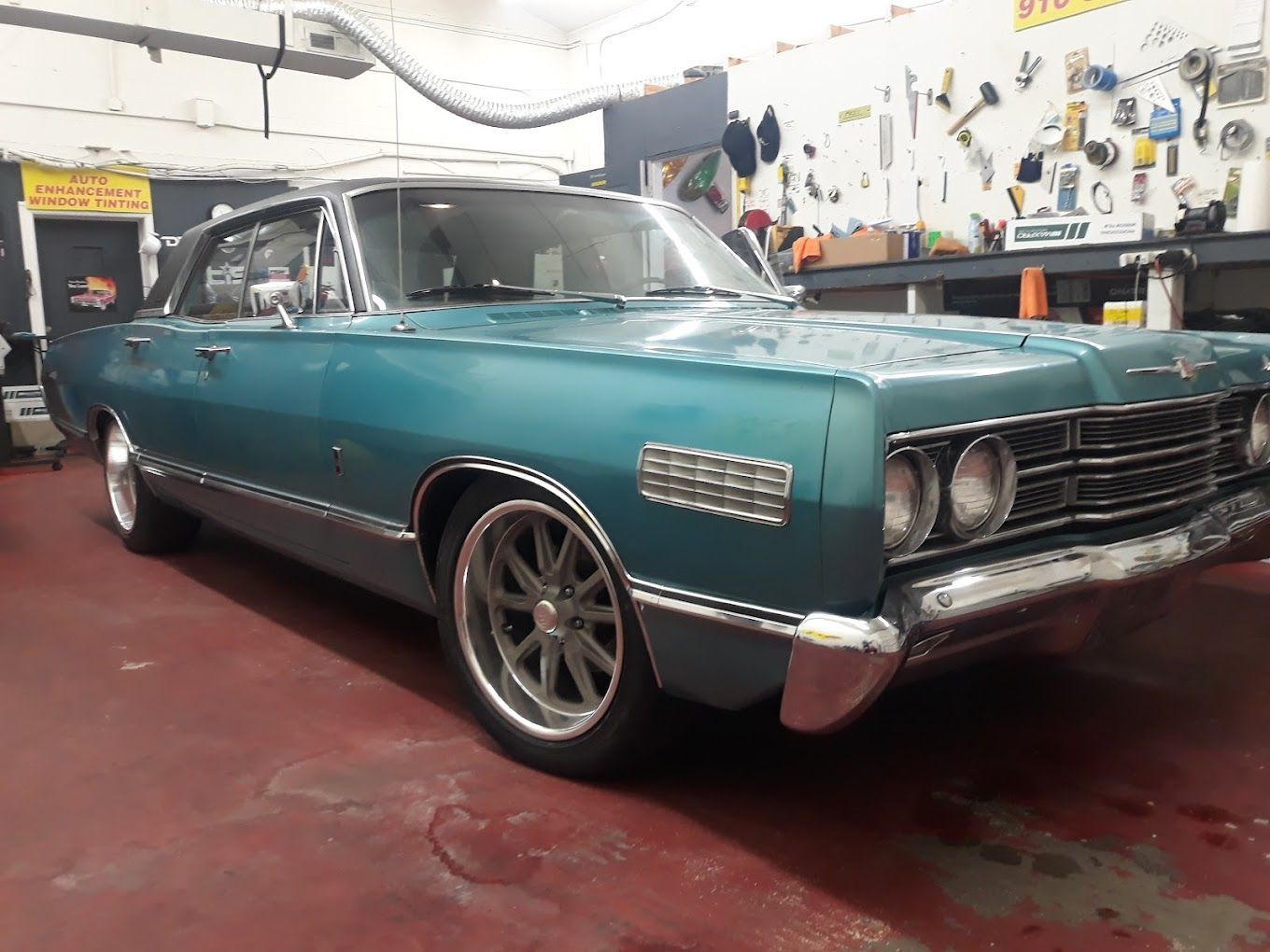 An old blue car is parked in a garage.