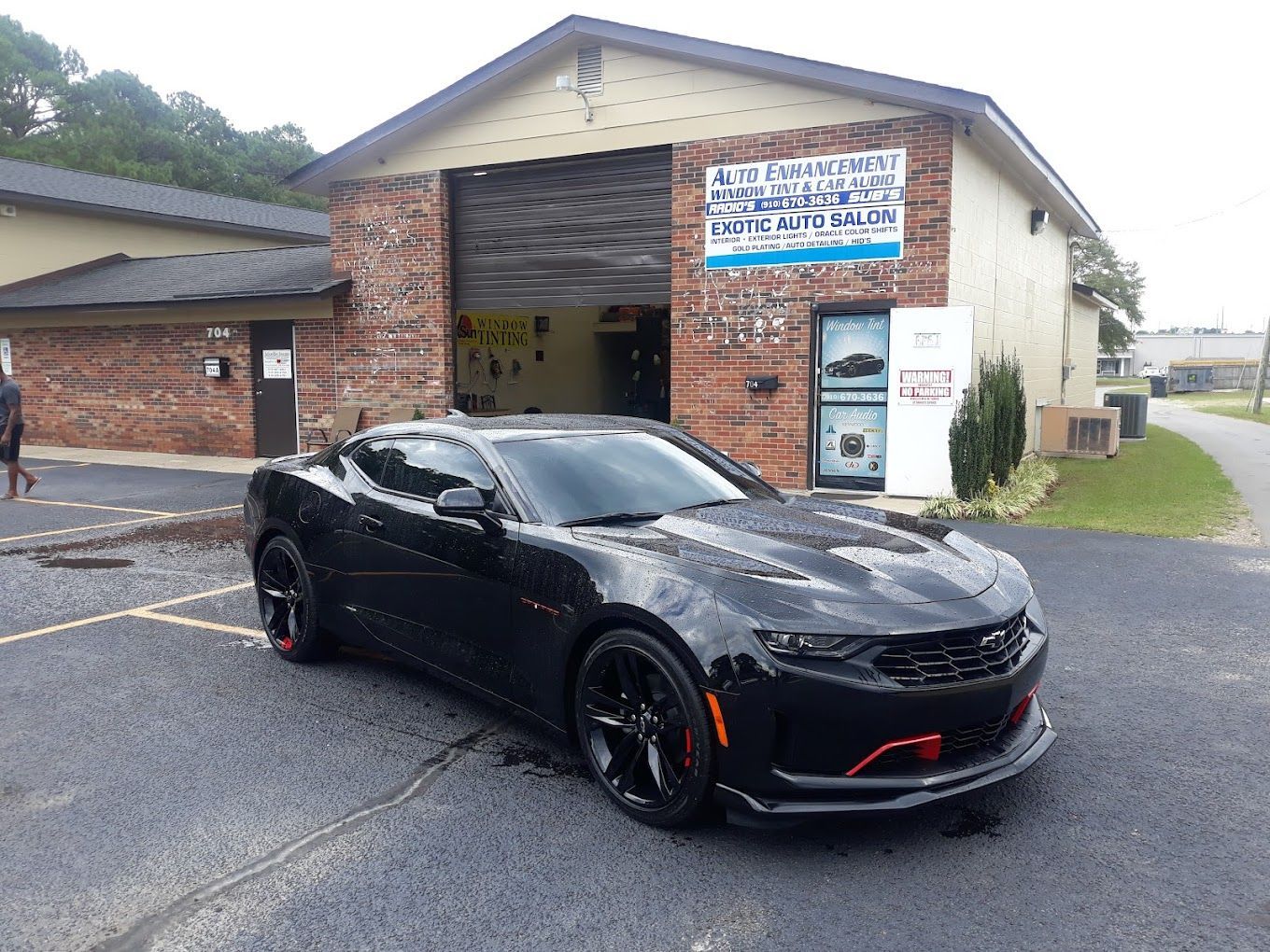 A black car is parked in front of a brick building.